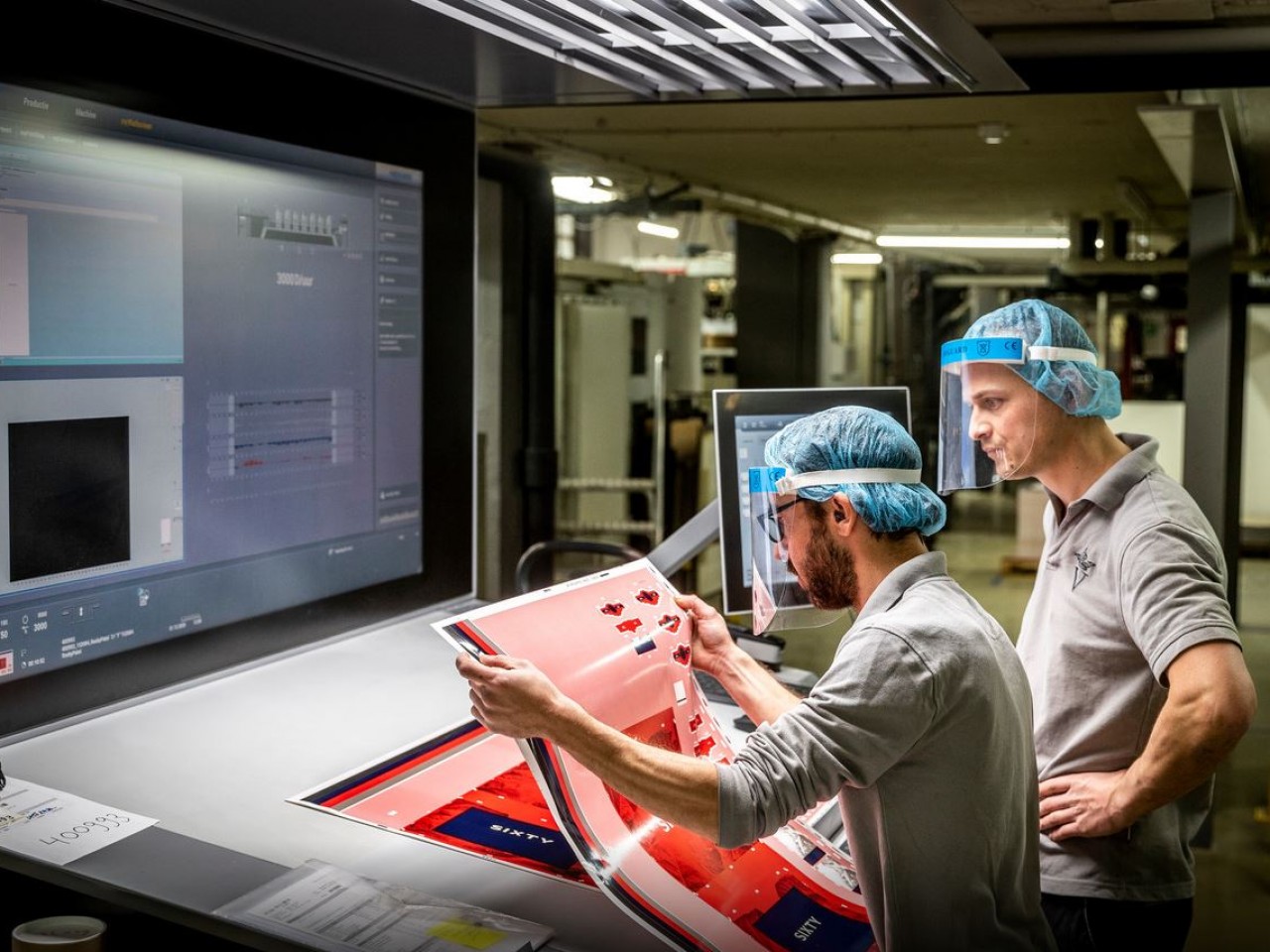 Employees Robert van Eijk (left) and Joost Middendorp (right) inspecting a printed sheet of Vrijdag Premium Printing. © Sem Wijnhoven / DCI Media